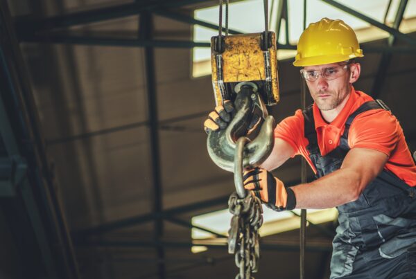 Construction Worker Operating an Overhead Crane at Building Site