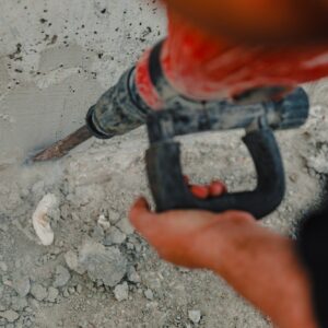 View of a worker at a construction site working with a rock-drill and digging the ground