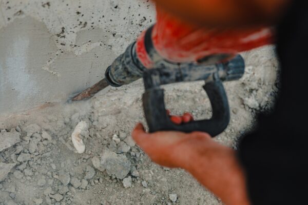 View of a worker at a construction site working with a rock-drill and digging the ground